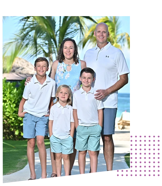 Dr. Denise Carrel and her family standing together outdoors near palm trees, posing for a group photo in a sunny setting.