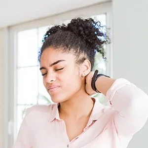 Individual holding the back of the neck, indicating discomfort or tension in the cervical area.